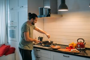 Man enjoying cooking with a safe range hood height above stove.